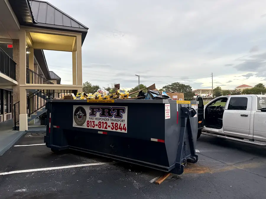 A dumpster filled with bagged debris outside a hotel