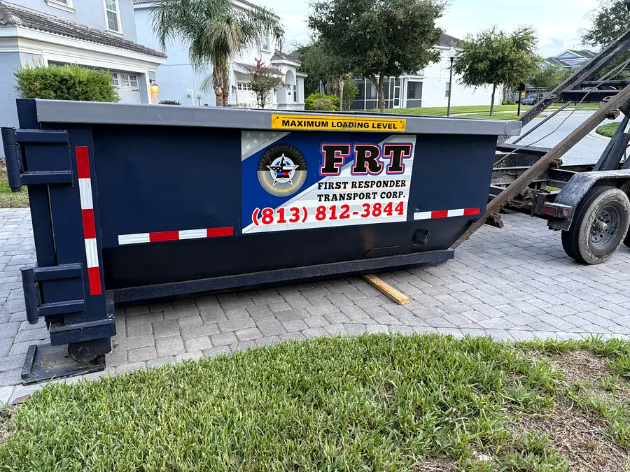An FRT roll-off dumpster placed on a paver driveway in front of a house