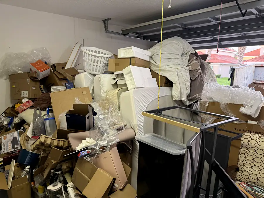 A garage packed floor to ceiling with boxes, mattresses and furniture before a cleanout