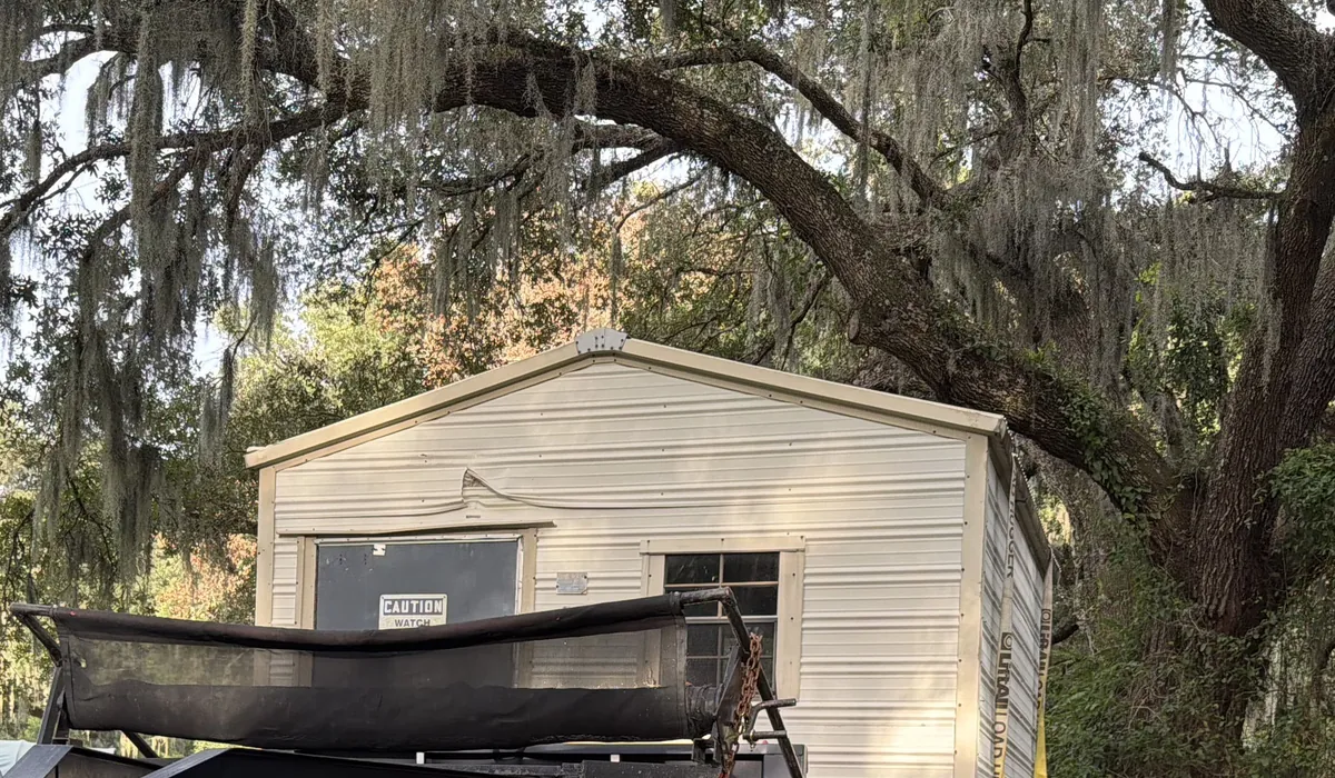 A shed loaded on the First Responder Transport gooseneck under live oaks
