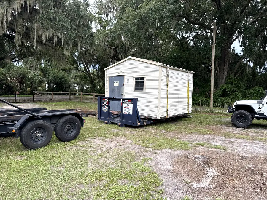 A shed loaded on the FRT trailer under oak trees